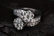 Two diamond rings featuring multiple small, clear diamonds arranged in a floral pattern set against a dark, contrasting background that enhances their sparkle.