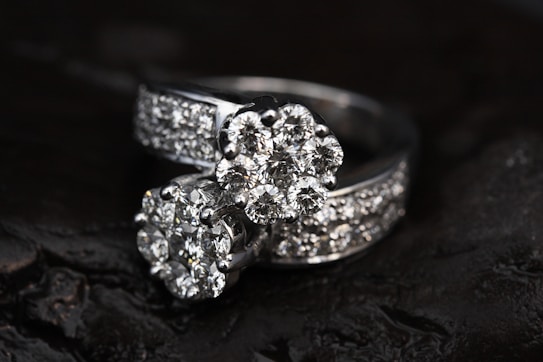 Two diamond rings featuring multiple small, clear diamonds arranged in a floral pattern set against a dark, contrasting background that enhances their sparkle.