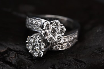 Two diamond rings featuring multiple small, clear diamonds arranged in a floral pattern set against a dark, contrasting background that enhances their sparkle.