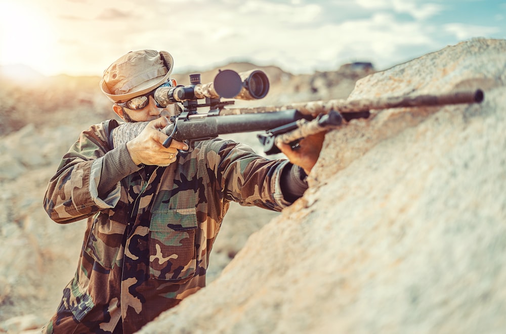 Hombre con traje militar de camuflaje verde y marrón sosteniendo un rifle