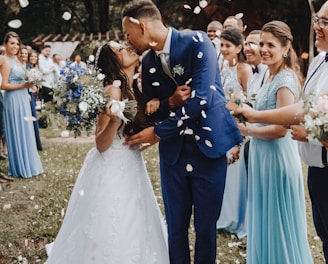 man in blue suit kissing woman in white wedding dress