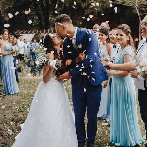 man in blue suit kissing woman in white wedding dress