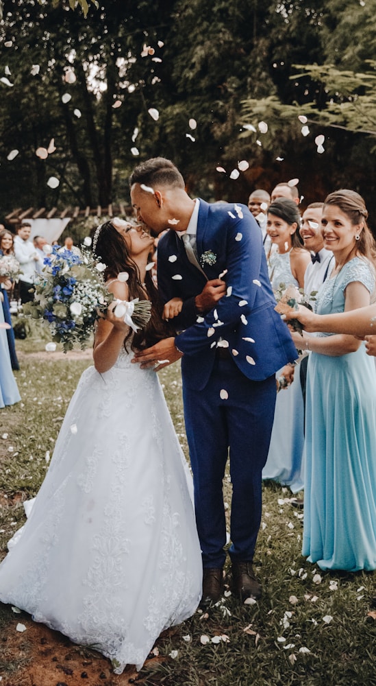 man in blue suit kissing woman in white wedding dress