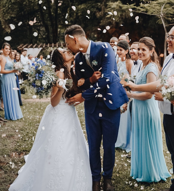 man in blue suit kissing woman in white wedding dress