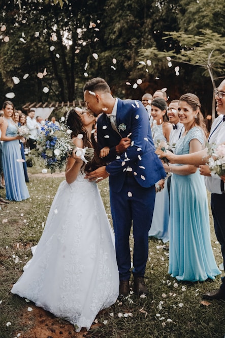 man in blue suit kissing woman in white wedding dress