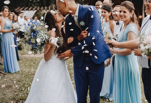 man in blue suit kissing woman in white wedding dress