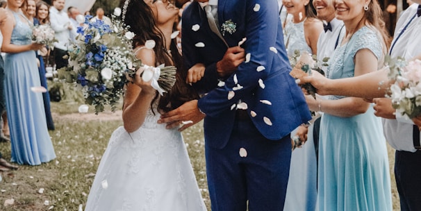 man in blue suit kissing woman in white wedding dress