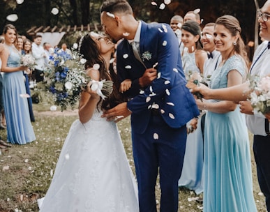 man in blue suit kissing woman in white wedding dress