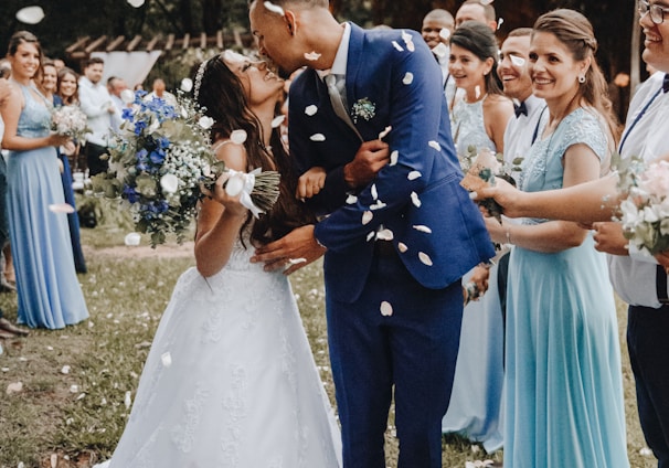 man in blue suit kissing woman in white wedding dress