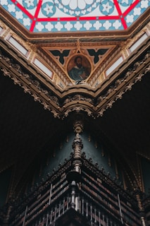 Portrait of Rafael de San Juan surrounded by antique religious books in a warmly lit study.