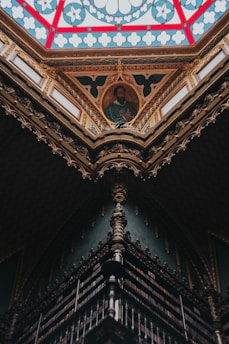 Portrait of Rafael de San Juan surrounded by antique religious books in a warmly lit study.