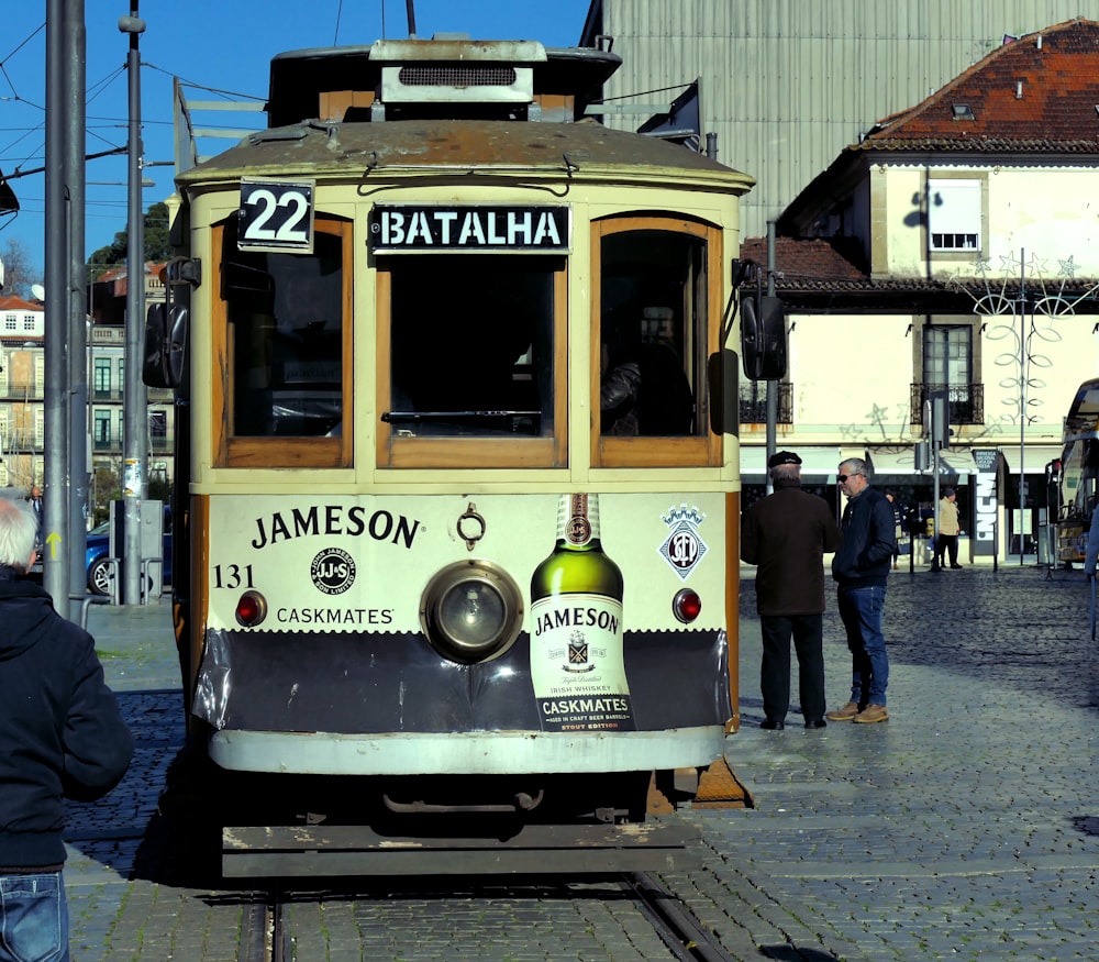 people walking on sidewalk near yellow tram during daytime