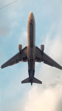 gray and yellow airplane under white clouds during daytime