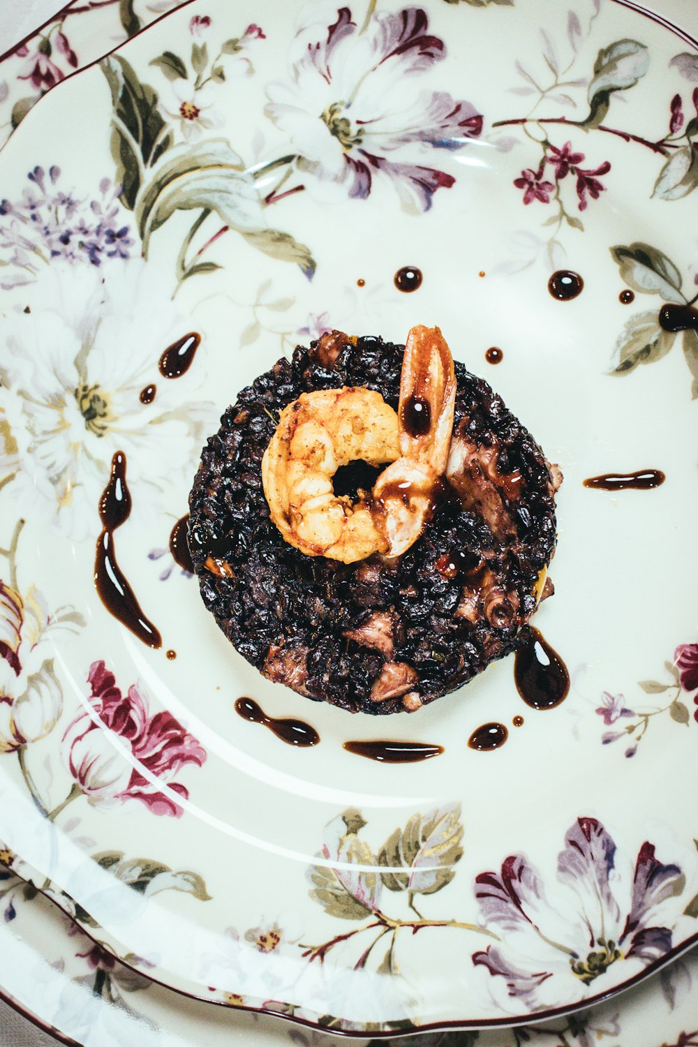 chocolate doughnut on white and red floral ceramic plate