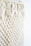 Intricate macramé pattern featuring woven and knotted cord designs, creating a textured and airy appearance. The focus is on the detailed craftsmanship of the knots against a soft, neutral background.