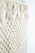 Intricate macramé pattern featuring woven and knotted cord designs, creating a textured and airy appearance. The focus is on the detailed craftsmanship of the knots against a soft, neutral background.