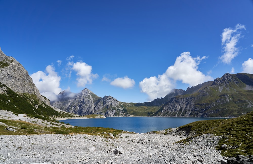 white and green mountains near body of water under blue sky during daytime