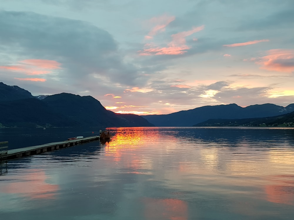 body of water near mountain during sunset