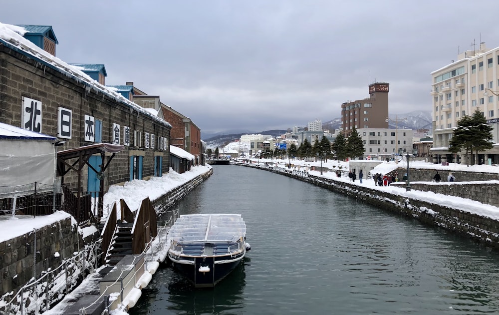 white and blue boat on water near brown concrete building during daytime