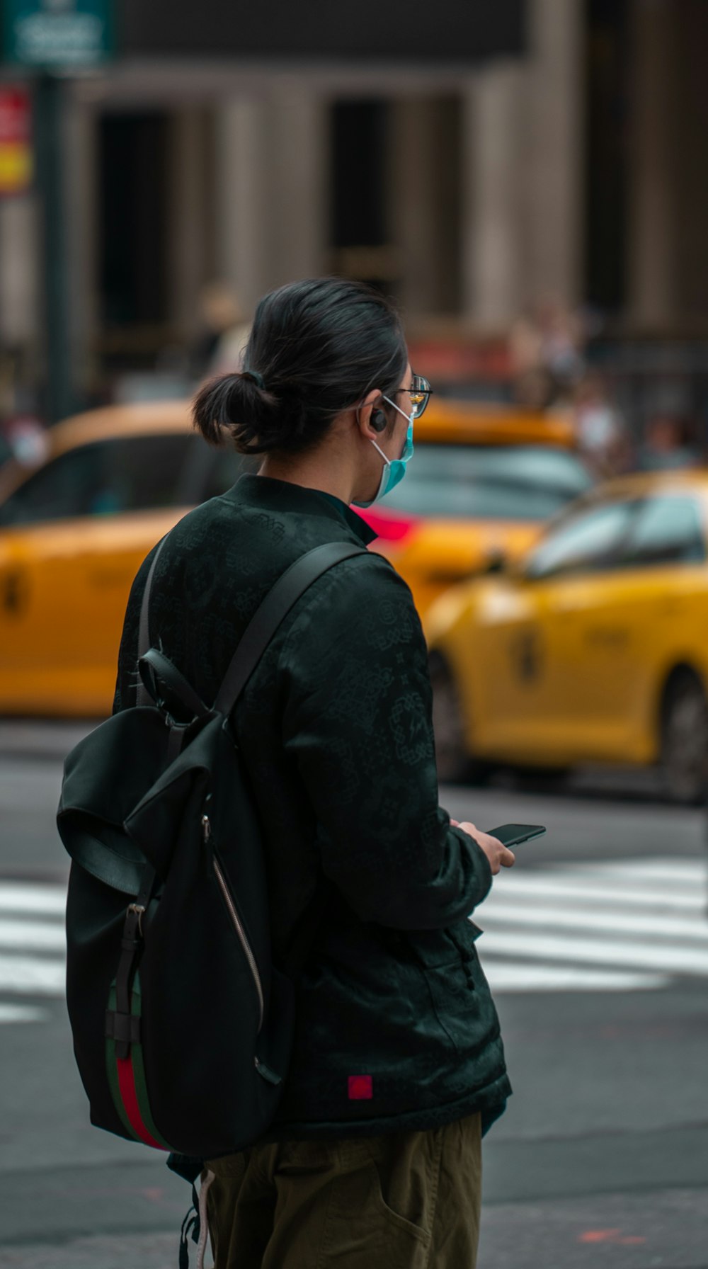 woman in black coat and black sunglasses standing on sidewalk during daytime