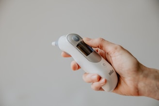 Digital thermometer held by a healthcare professional ready to take a patient's temperature.