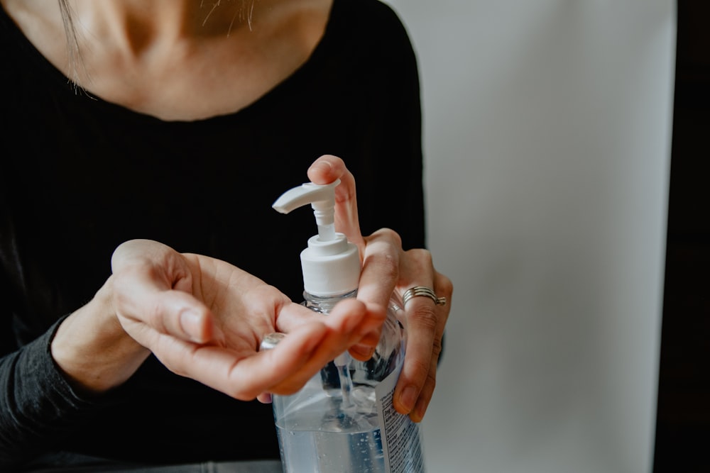 femme en chemise noire tenant une bouteille en plastique blanche