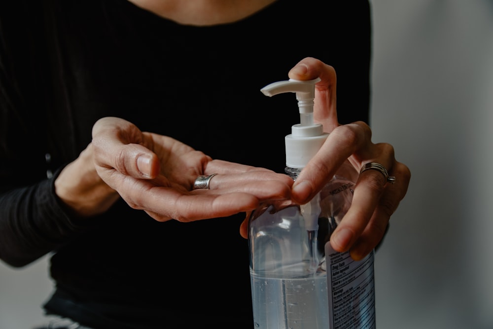 Persona sosteniendo una botella de spray de plástico blanco