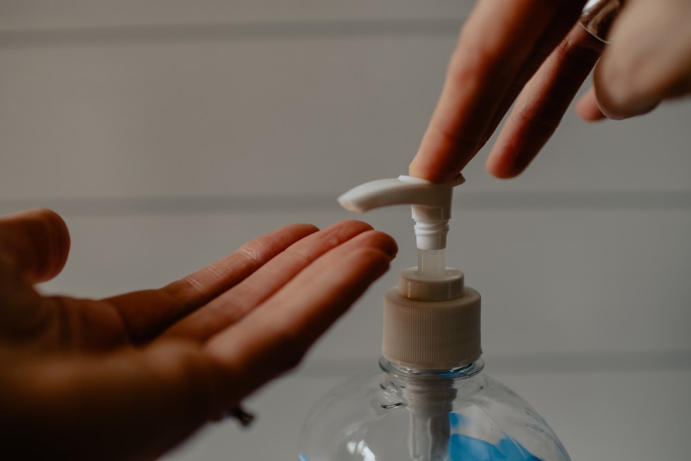 personne tenant une bouteille à pompe en plastique blanc