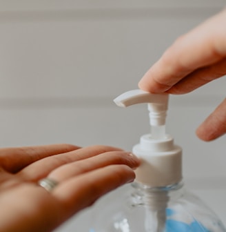 person holding white plastic pump bottle