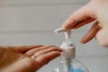 person holding white plastic pump bottle