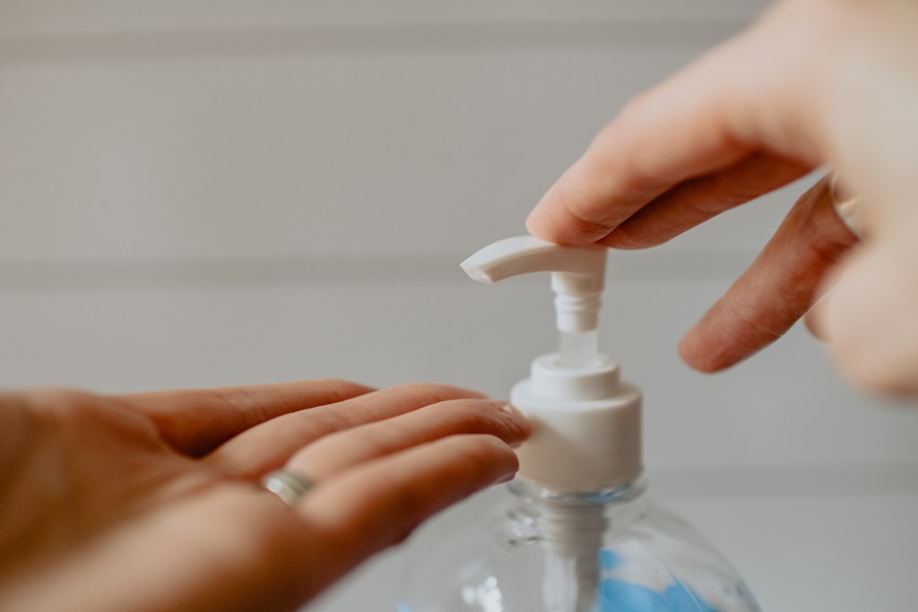 return to work cleaning station person holding white plastic pump santizing bottle