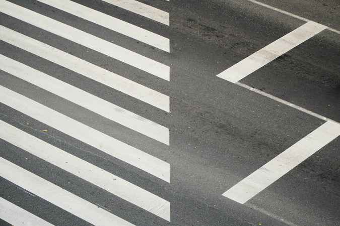 White crosswalk stripes painted across a neighborhood street near a school zone