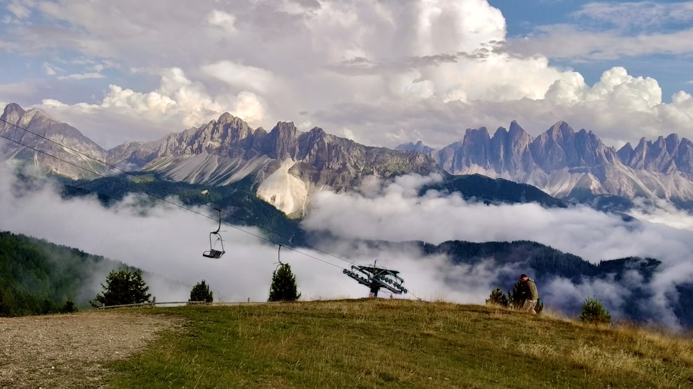 green grass field near mountain under white clouds during daytime