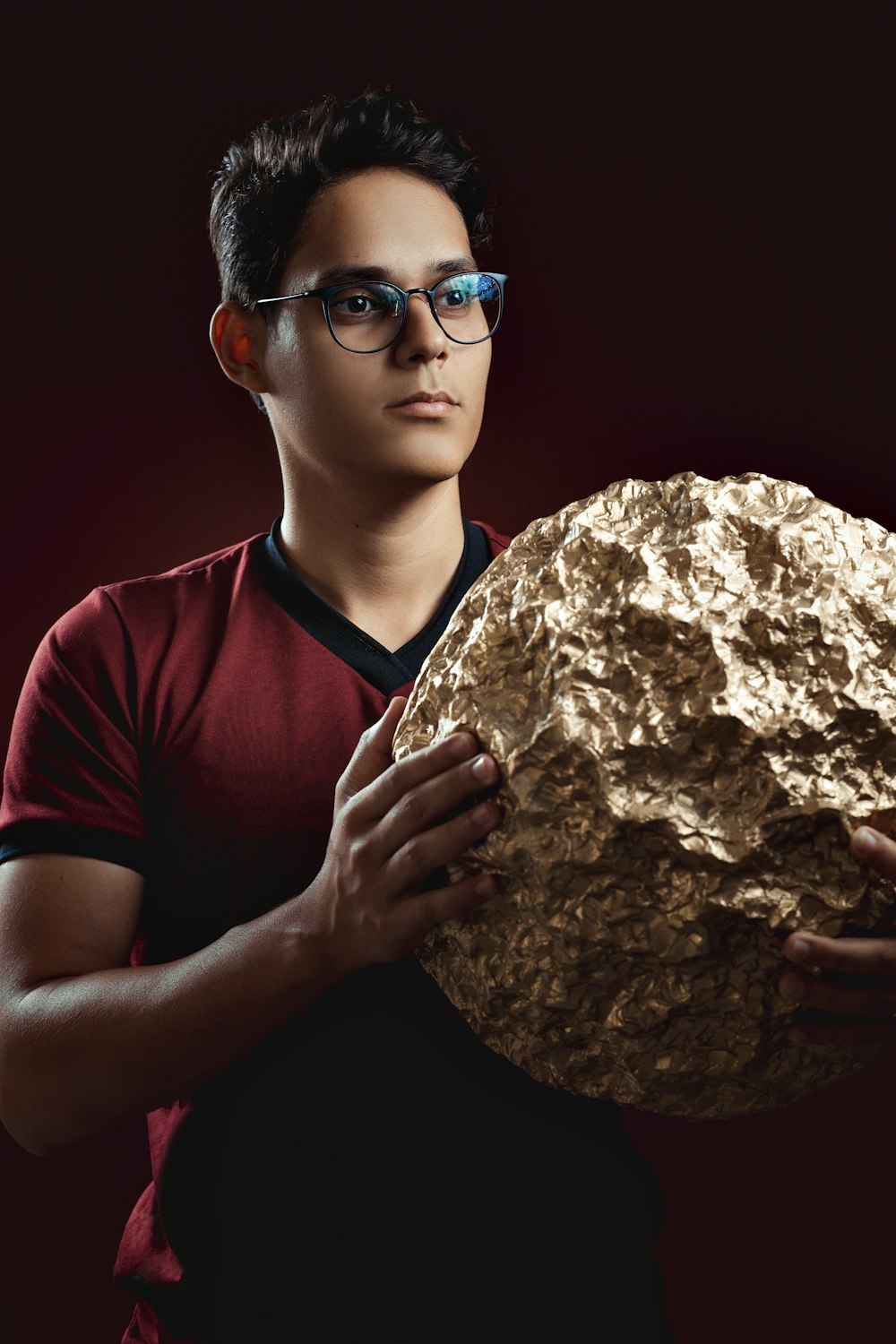 boy in red crew neck t-shirt holding brown stone