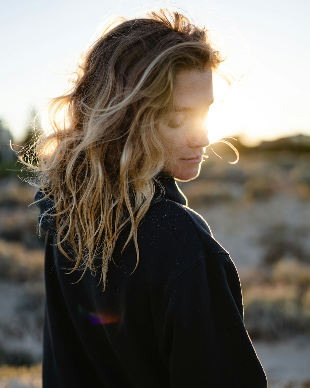 girl in black jacket standing on brown field during daytime