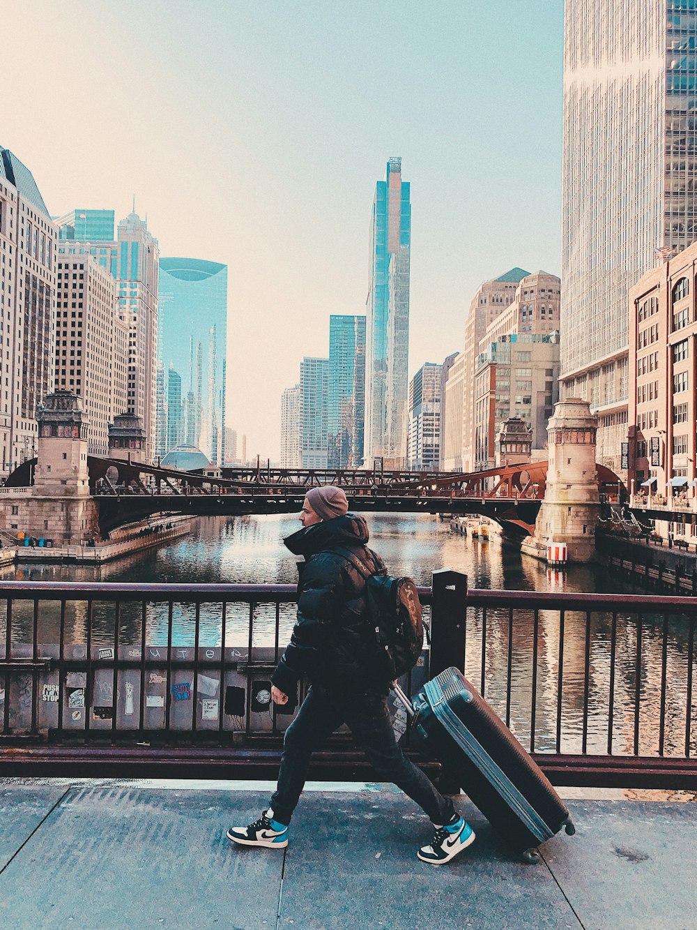 man in black jacket sitting on black metal railings near body of water during daytime