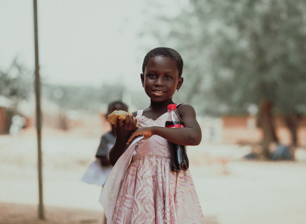 girl in pink dress holding baby in white dress during daytime