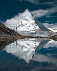 snow covered mountain near lake under blue sky during daytime