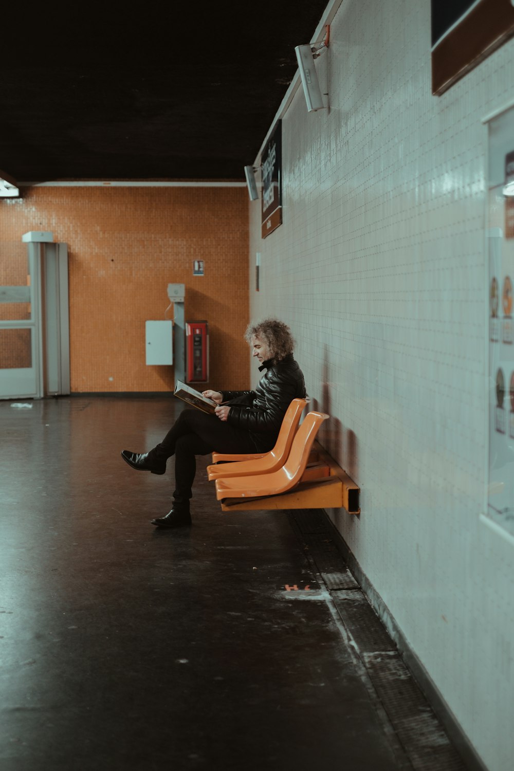 woman in black jacket sitting on brown wooden bench