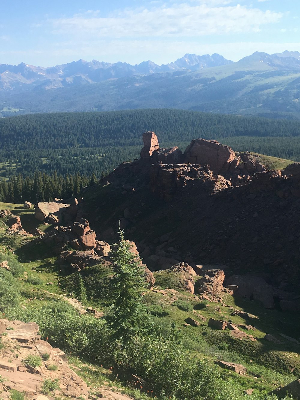 person sitting on rock formation near green trees during daytime