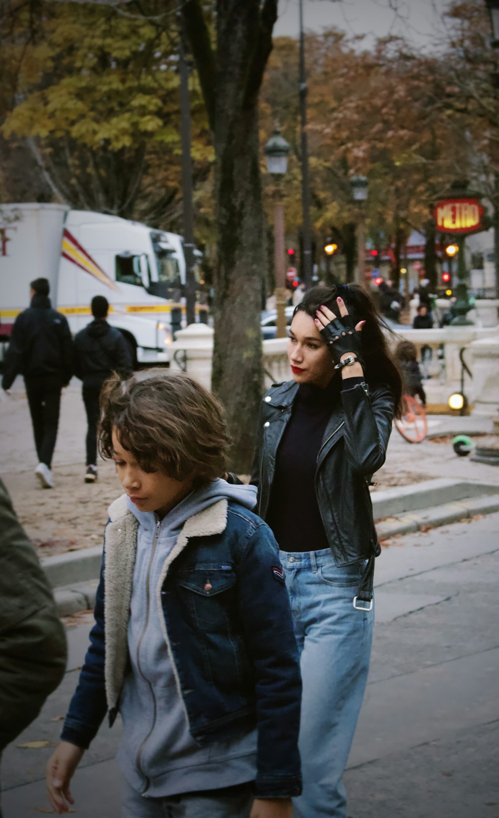 woman in black leather jacket kissing girl in gray jacket during daytime