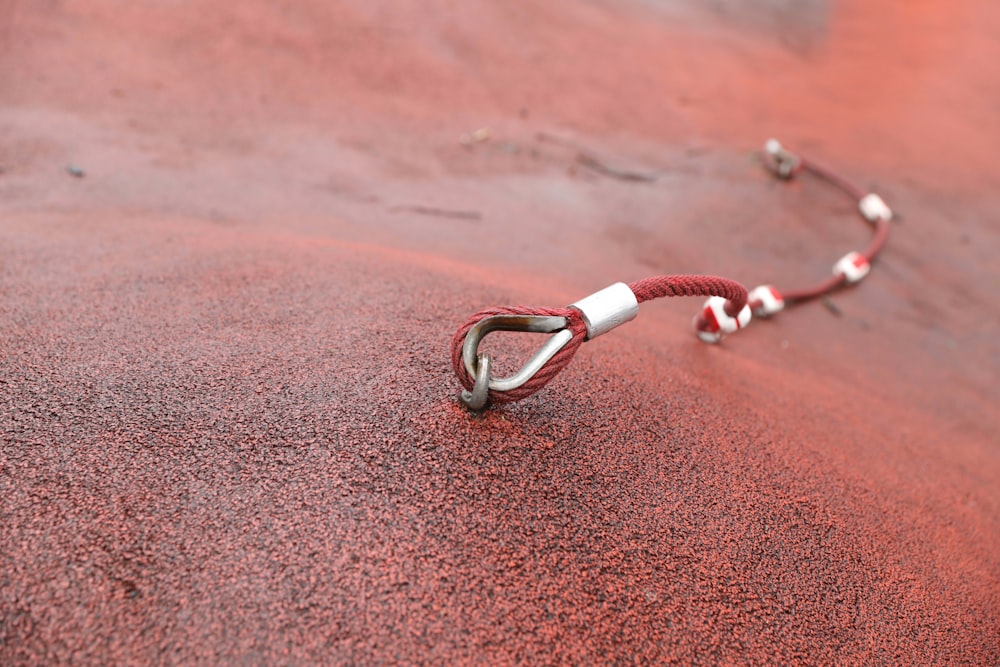 silver and red beaded bracelet on brown sand
