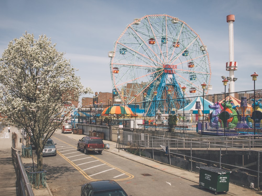 ferris wheel near cars on road during daytime