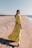 A woman enjoying a sunny day at the beach, wearing a flowing summer dress in bright yellow.