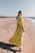 A woman enjoying a sunny day at the beach, wearing a flowing summer dress in bright yellow.