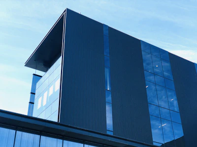 A sleek glass-front commercial building reflecting the clear blue San Francisco sky during daylight.