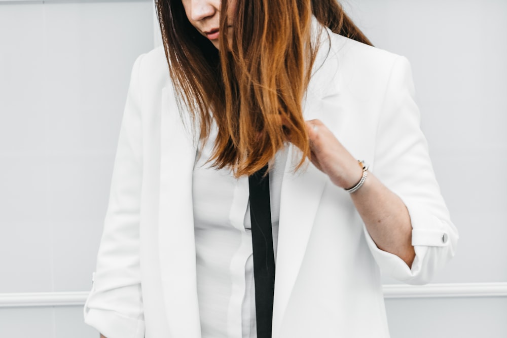 woman in white blazer with black necktie