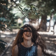 A joyful woman in a flowing ethnic gown, laughing under soft golden light in a lush garden setting.