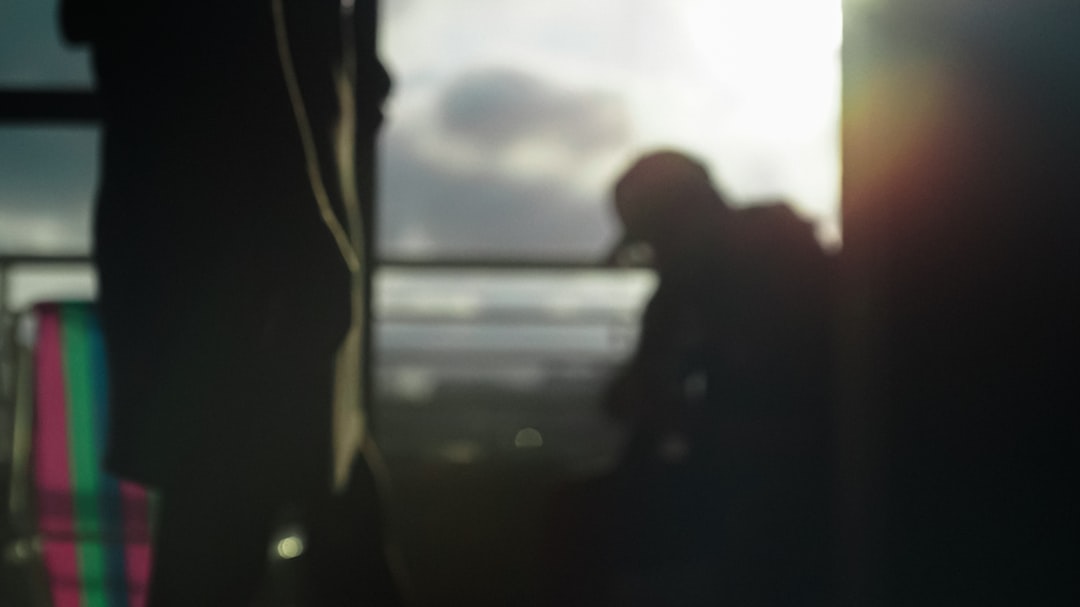 silhouette of man standing near body of water during daytime