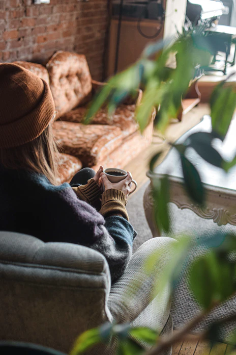 a woman sitting on a couch holding a cup of coffee